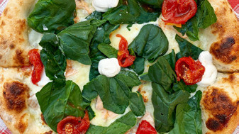 Pizza topped with fresh arugula and tomatoes